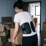 Young woman moving house wearing the lumbar belt