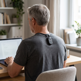 Older man at his desk wearing the posture sensor, seen from behind